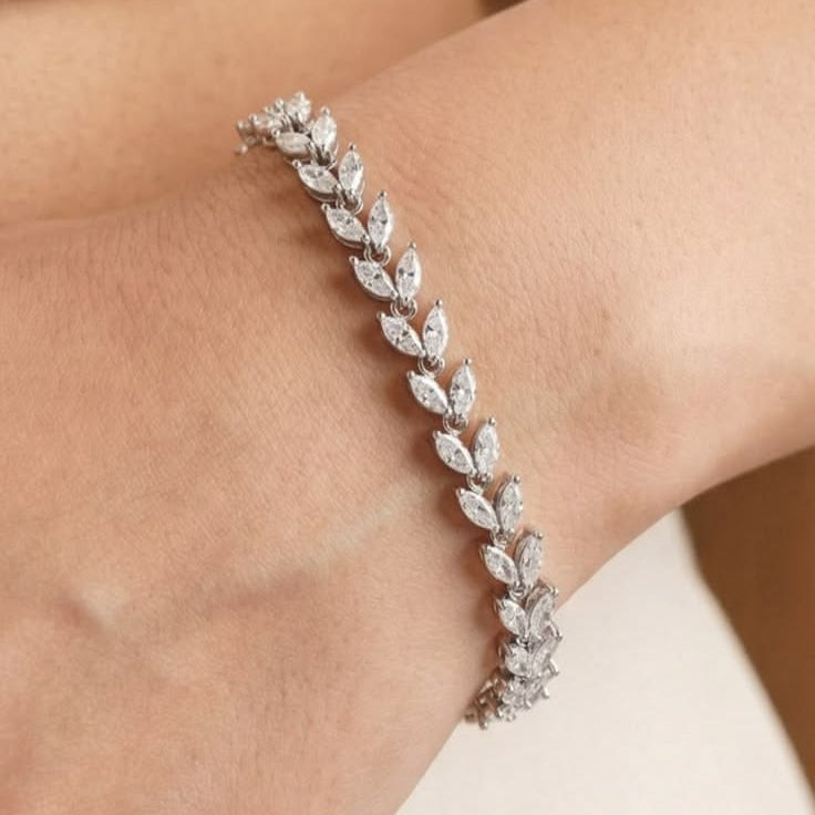 A yellow gold tennis bracelet, featuring a double row of clustered marquise-cut diamonds angled to look like repeating leaves on a vine.