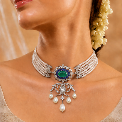 Exude timeless majesty with the Royal Heirloom Emerald & Pearl Choker Centerpiece (Model NCK3112). This stunning statement piece features a rich, 14x10 mm oval emerald surrounded by brilliant blue stones and 279 diamonds, all finished with elegant, cascading teardrop pearls. Expertly crafted in premium 14kt or 18kt gold, this centerpiece is designed for the modern royal. Whether for a bridal look or a high-fashion ensemble, add unparalleled luxury to your jewelry collection with this intricate masterpiece.