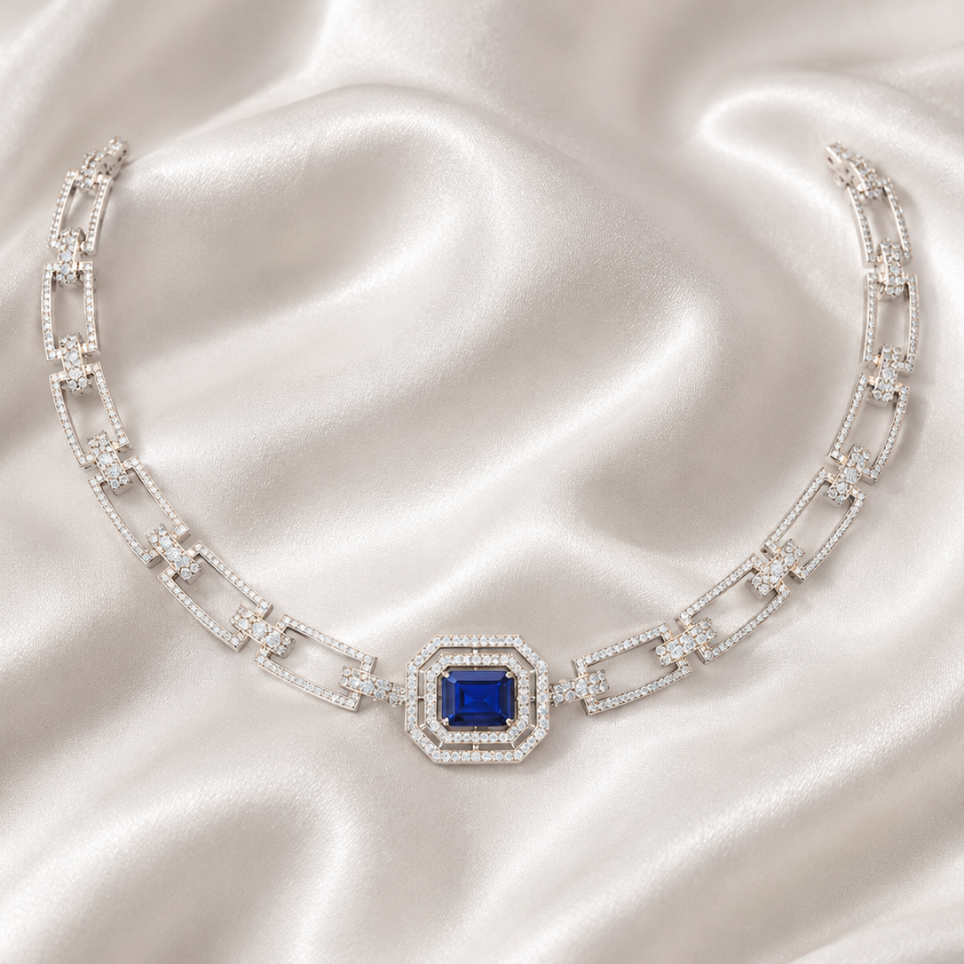 White gold and diamond link necklace with a central emerald-cut blue sapphire gemstone