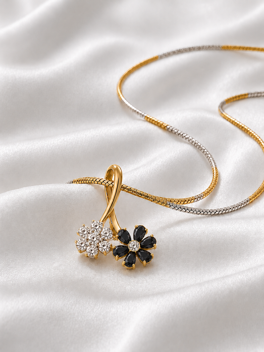 A yellow gold dual flower pendant necklace featuring one flower made of sparkling white diamonds and another made of rich black gemstones.