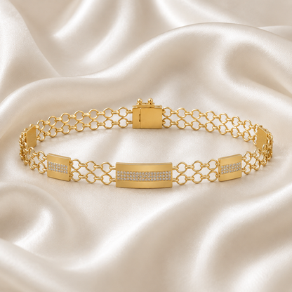 "A yellow gold bracelet featuring a central rectangular bar accented with small diamonds, connected by a double row of open circle chain links on a white silk background