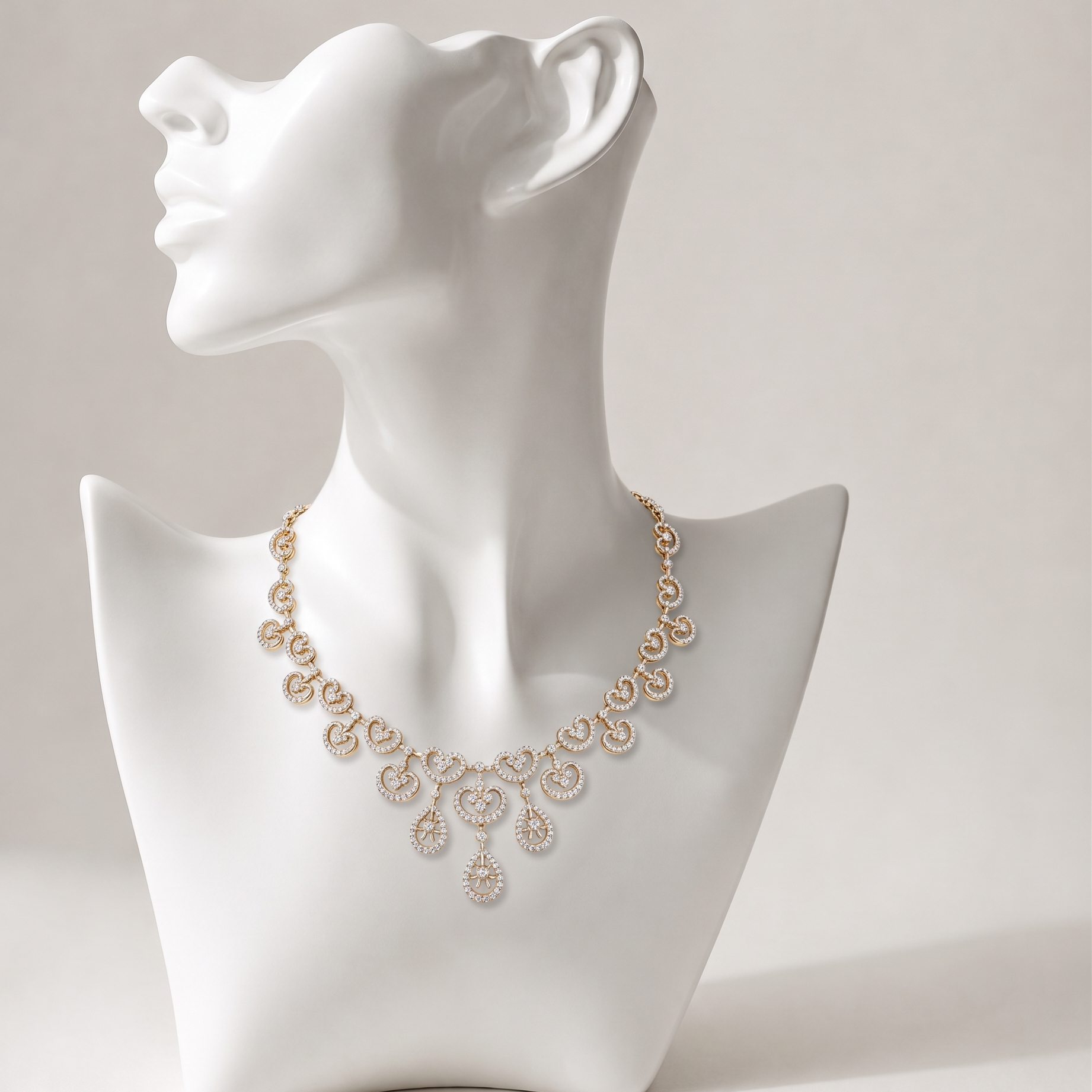 Yellow gold necklace and matching drop earrings set featuring diamond-studded heart scrolls and open-work dangling teardrops.