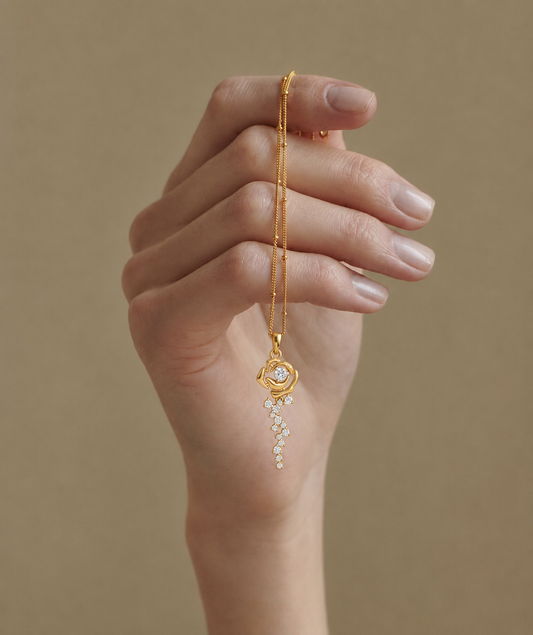 The Forever Rose pendant in yellow gold featuring a diamond center and a cascading trail of falling petal diamonds.