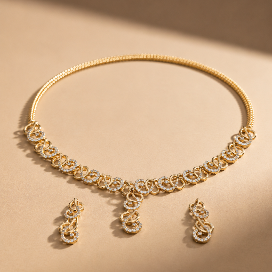 Yellow gold necklace and matching drop earrings set featuring interlocking swirl links studded with diamonds and a tiered central drop.