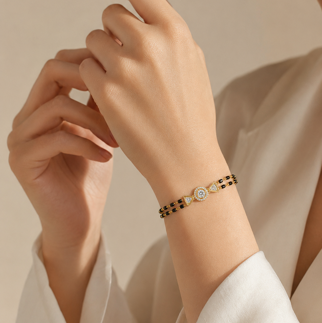 A yellow gold bracelet featuring two rows of small black beads connected to a central round diamond halo charm flanked by two gold triangle accents.
