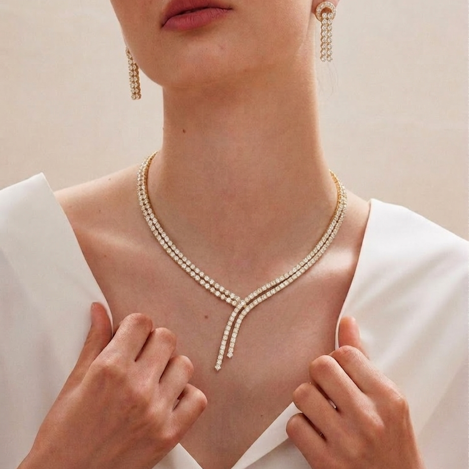 A yellow gold necklace made of two rows of small diamonds that cross over each other in the front with hanging ends.