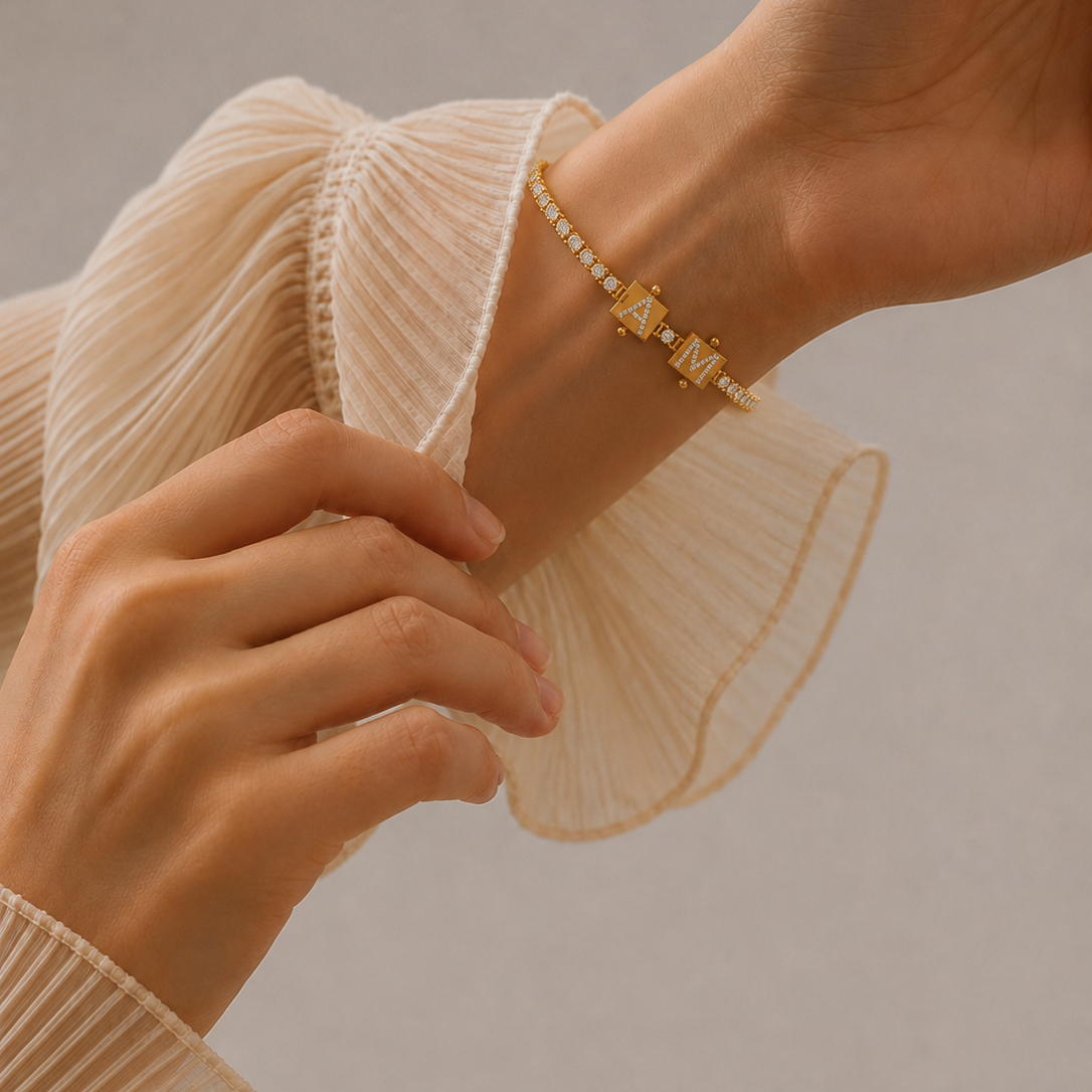 A flat-lay view of a yellow gold diamond tennis bracelet featuring blank square metal charms on both ends.