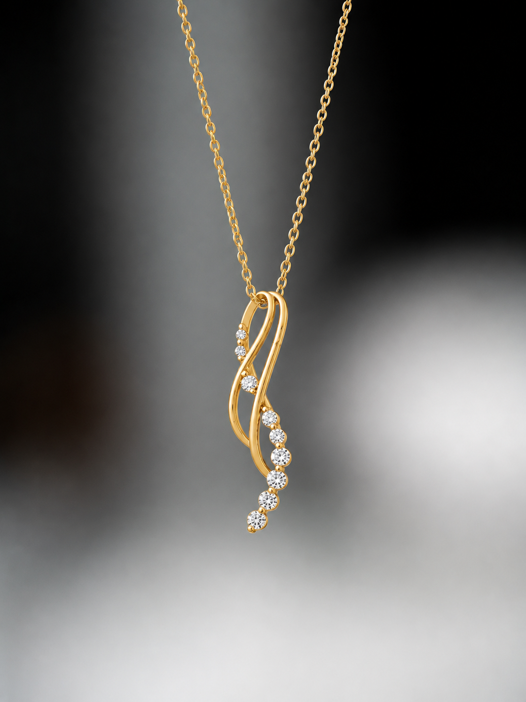 Yellow gold pendant featuring a curved wave design accented with a row of round diamonds.