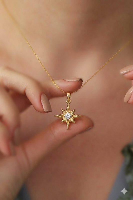 A yellow gold necklace with a pendant shaped like a multi-pointed North Star, featuring a single round diamond in the center.