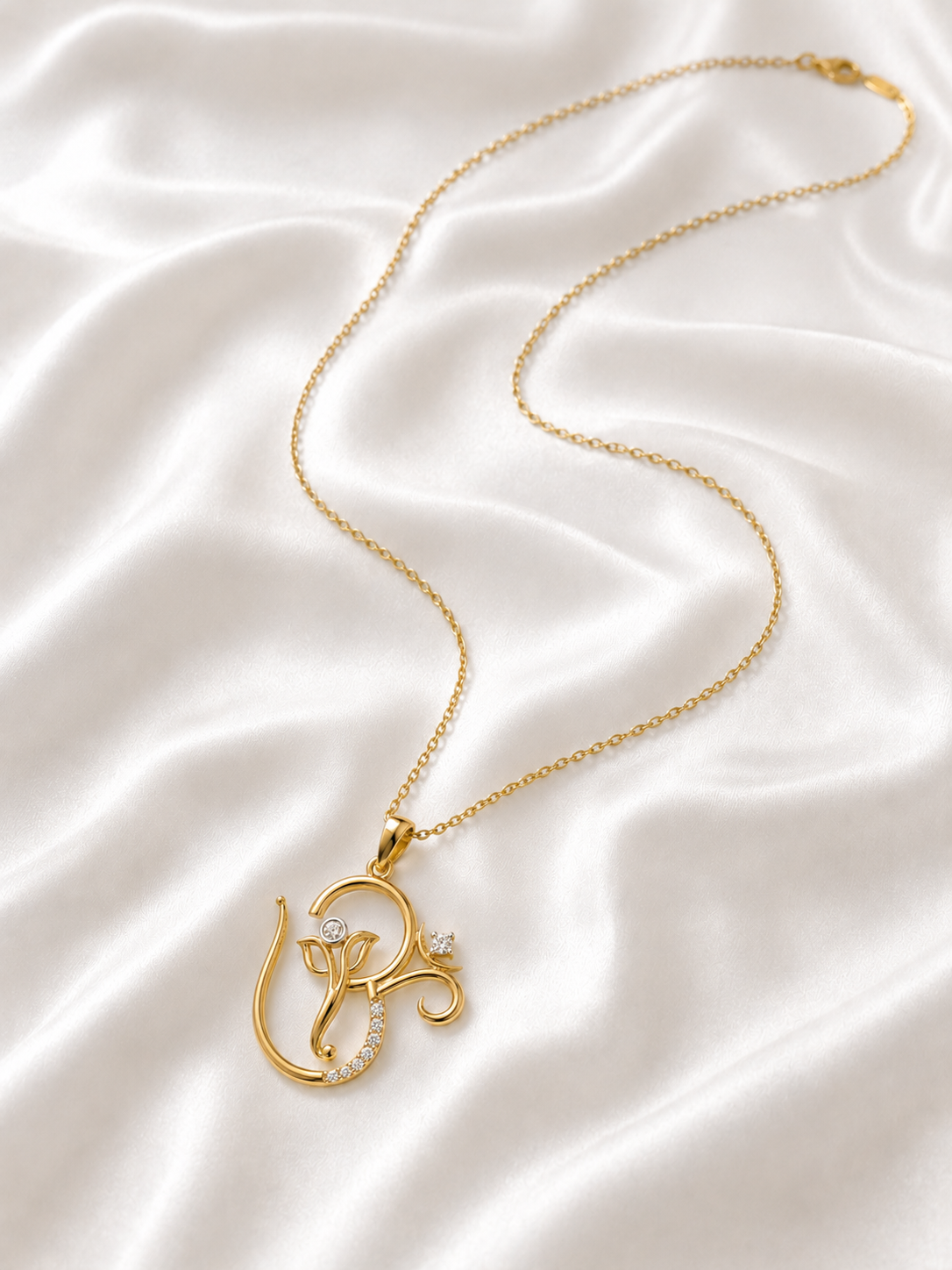 Gold pendant necklace shaped like the Om symbol and Lord Ganesha, decorated with small diamond.