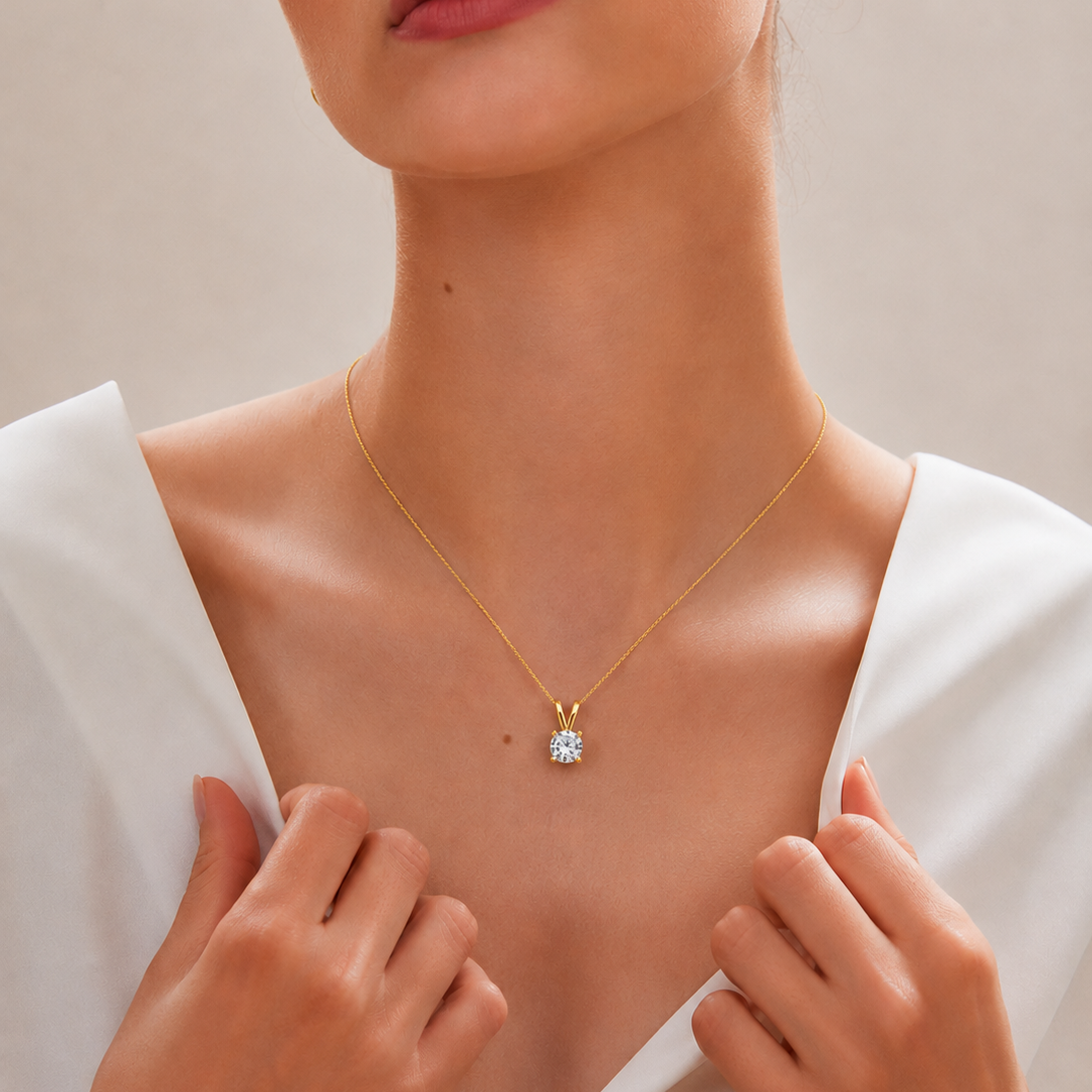 A yellow gold pendant featuring a single round brilliant-cut diamond solitaire secured in a clean four-prong setting with a V-shaped bail