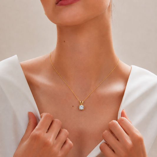 A yellow gold pendant featuring a single round brilliant-cut diamond solitaire secured in a clean four-prong setting with a V-shaped bail