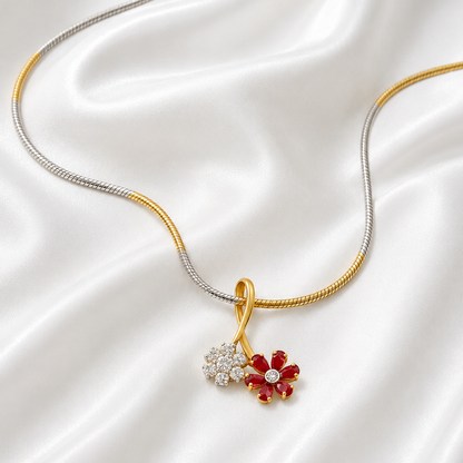 A yellow gold dual flower pendant necklace featuring one flower made of sparkling white diamonds and another made of rich red rubies.
