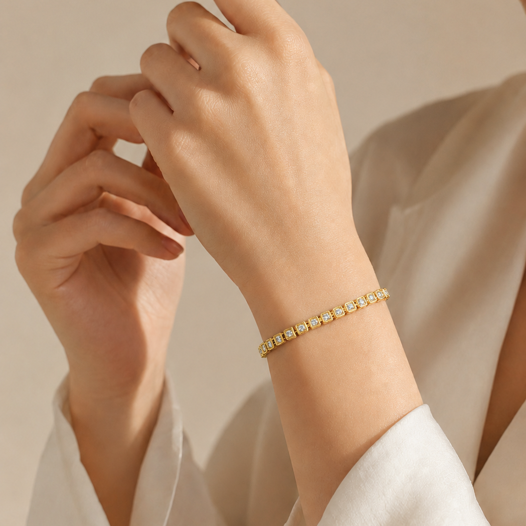 A yellow gold tennis bracelet featuring small round diamonds enclosed in repeating square bezel links with a textured milgrain border