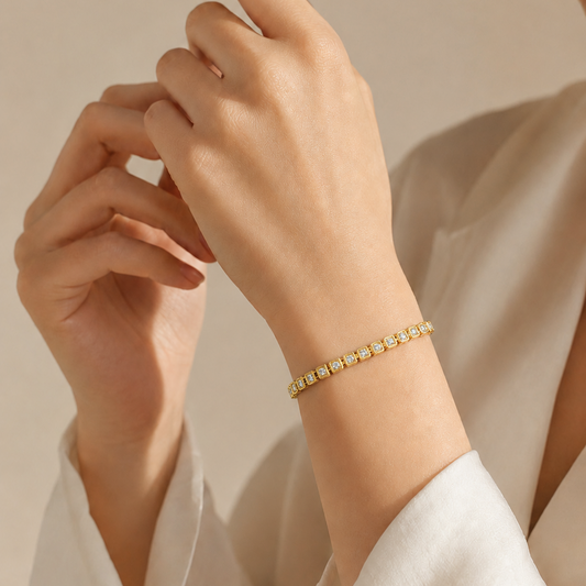 A yellow gold tennis bracelet featuring small round diamonds enclosed in repeating square bezel links with a textured milgrain border