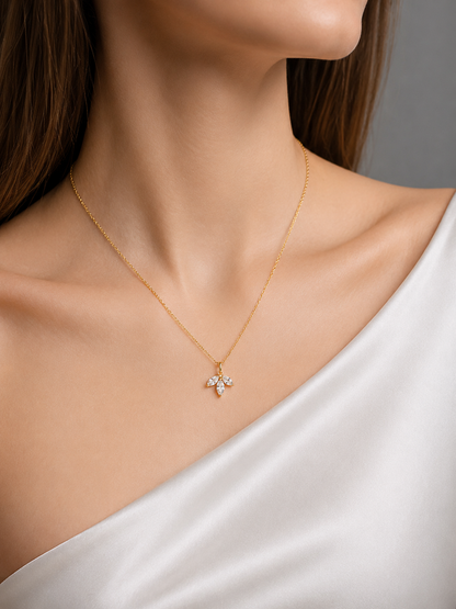 A yellow gold pendant necklace featuring a small cluster of three clear marquise stones shaped like a delicate leaf or flower bud.