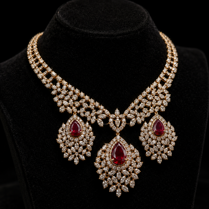 An ornate yellow gold bridal choker showcasing a multi-row band of diamond clusters and three large, intricate, pear-shaped pendants. Each drop features a rich pear-cut ruby surrounded by dazzling marquise-cut diamond surrounds, radiating royal elegance.