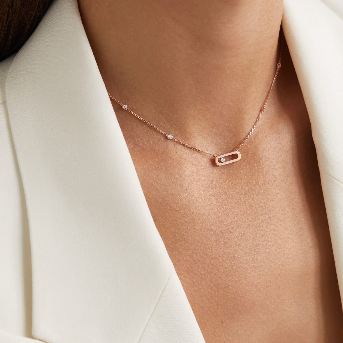 A delicate rose gold chain necklace featuring an elongated open oval loop pendant with a single sliding round diamond floating inside, accented by small bezel-set diamonds along the chain.